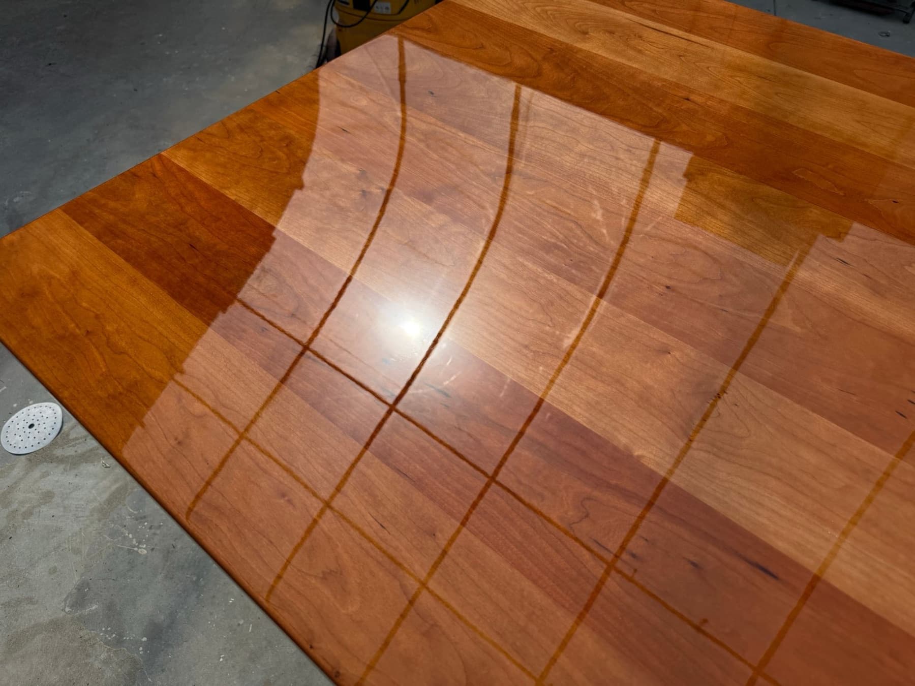 A cherry panel half finished in gloss marine varnish, showing the line between bare wood and the built-up finish.